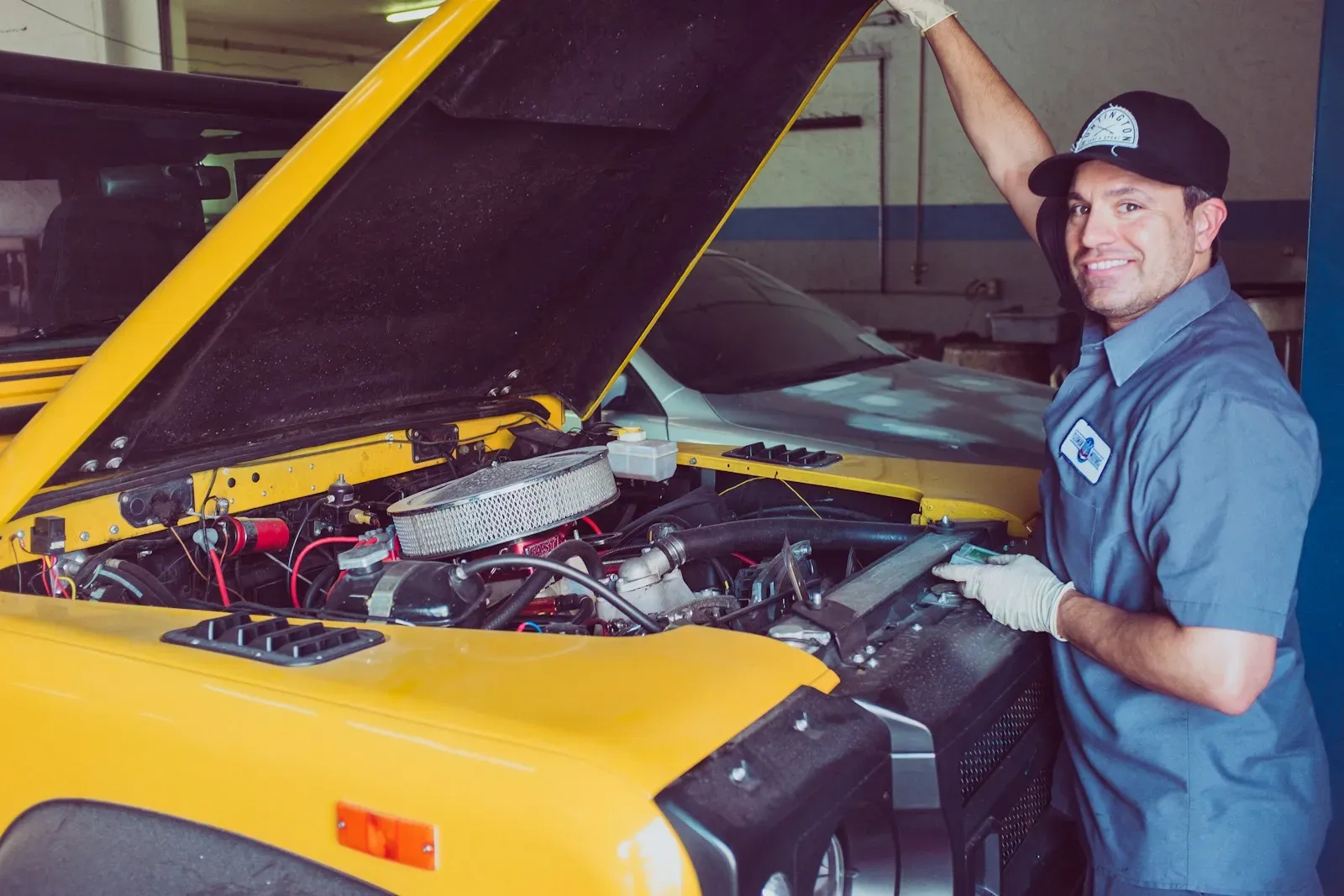 Mecánico sonriente trabajando en el motor de un auto