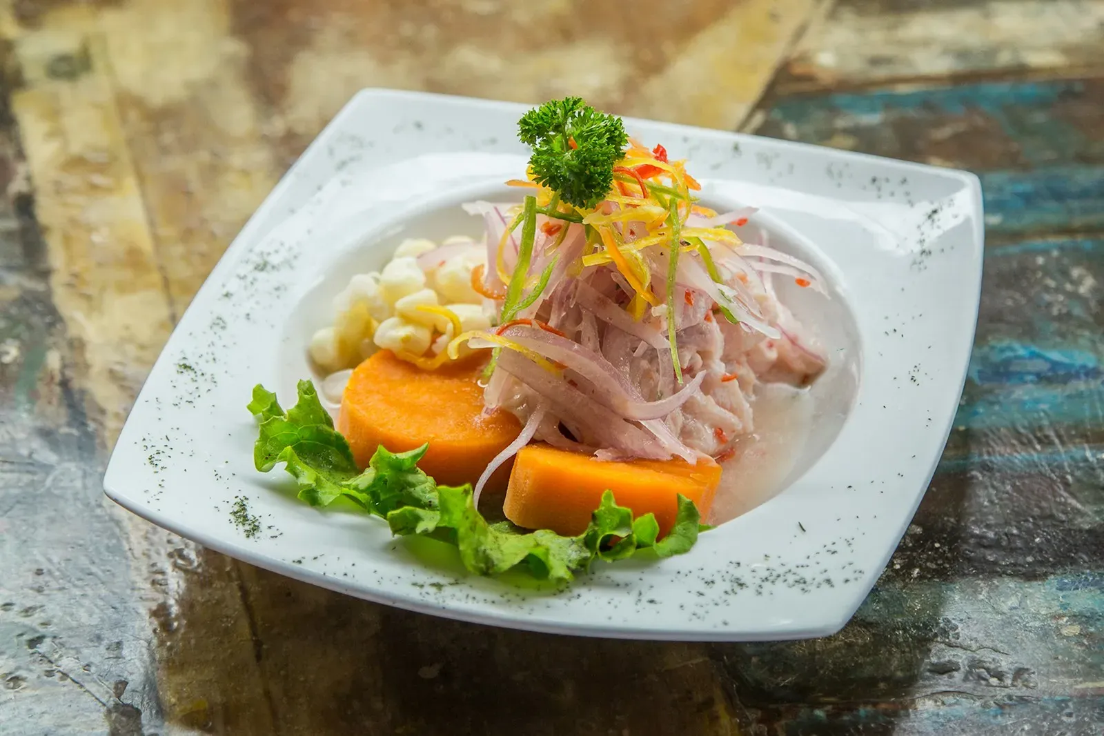 Plato de ceviche con camote, choclo y lechuga